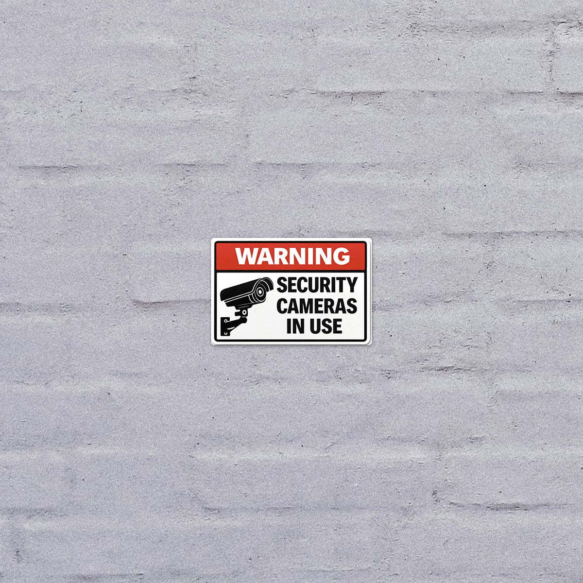 Security Camera Warning sticker on a painted brick wall